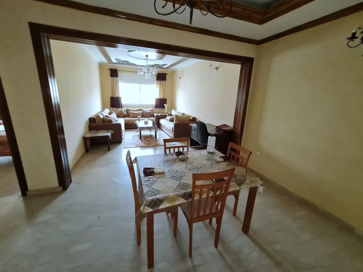 Salle à manger d'un appartement, table pour six, et le salon au-delà d'une large arche