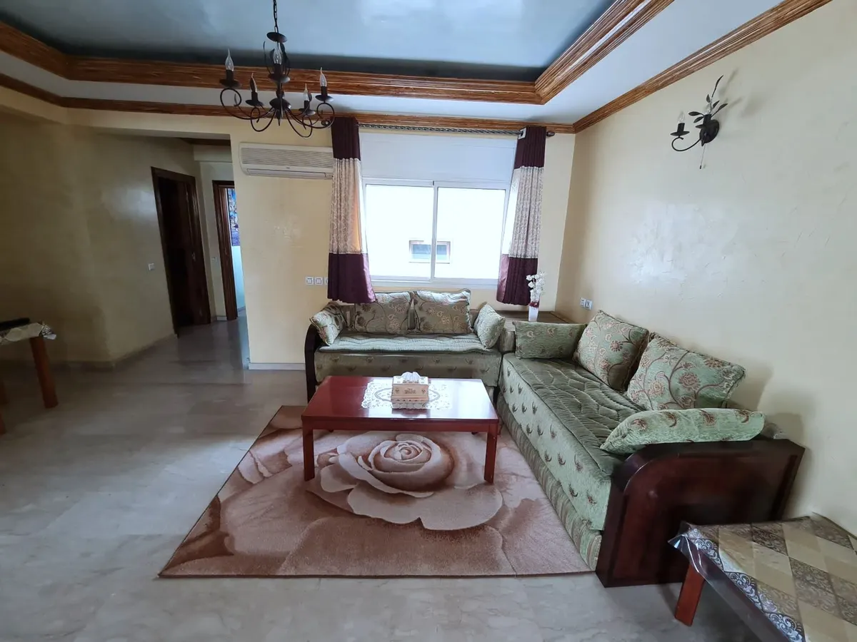 Salon marocain avec banquettes vertes, table basse et tapis rose