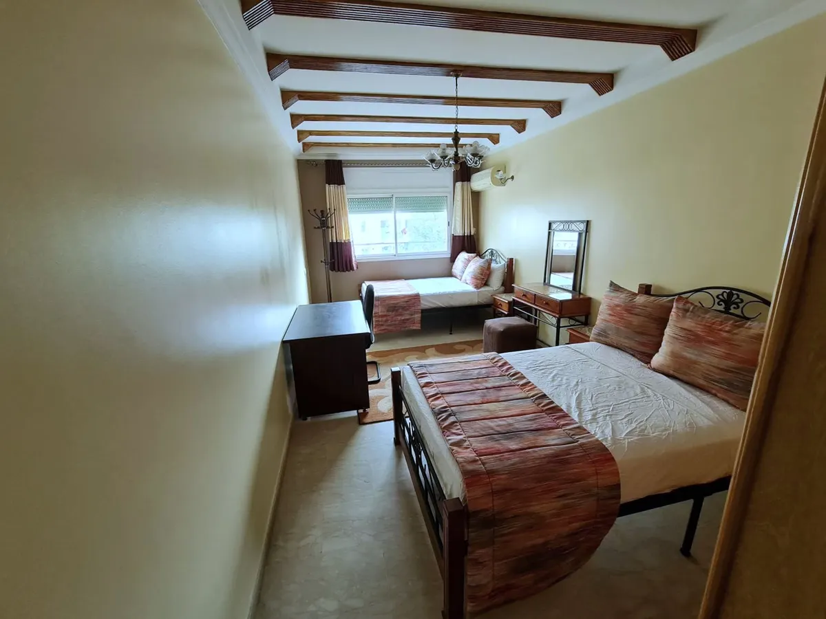Chambre sous poutres peintes, lit double en fer forgé et lit simple