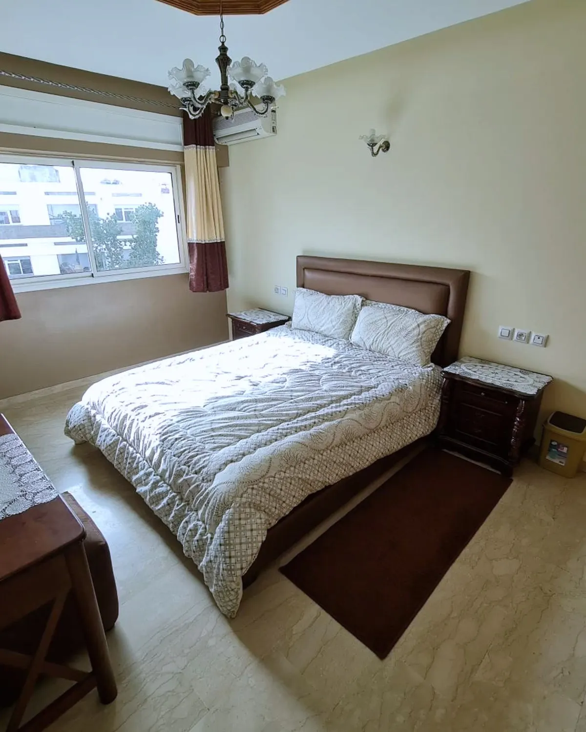 Chambre avec lit double face à la fenêtre, tables de chevet et portemanteau